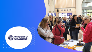 A group of women are standing in a room at the University of Greenwich, looking at brochures.