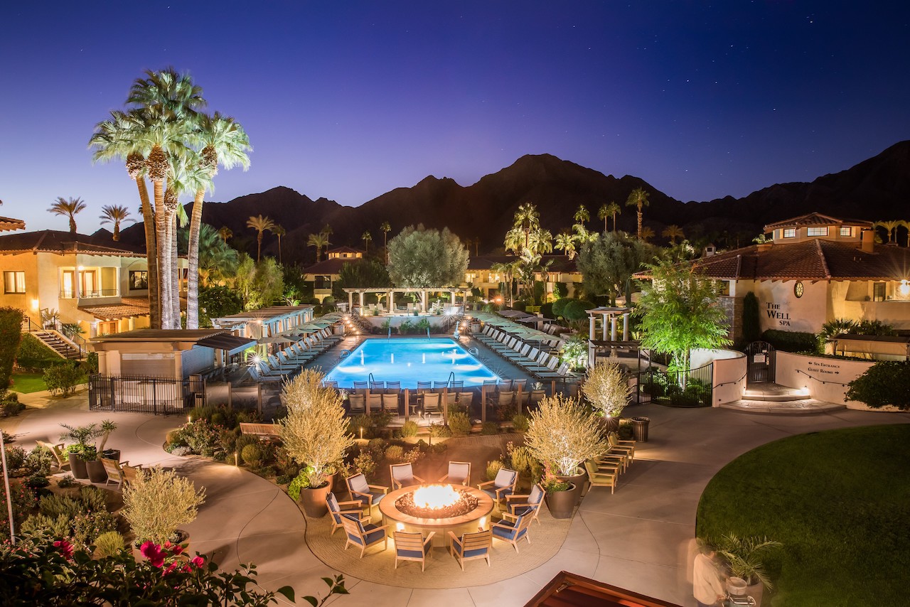 Miramonte Resort & Spa's pool area, featuring lounge chairs, fire pit, and mountain backdrop at night.