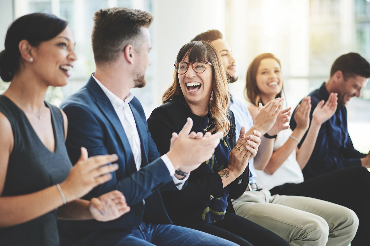 Group of happy business people clapping hands while sitting in the conference room.