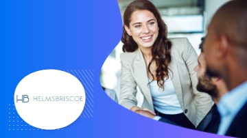 A woman is smiling at a man who is looking at her with the text HB HelmsBriscoe.