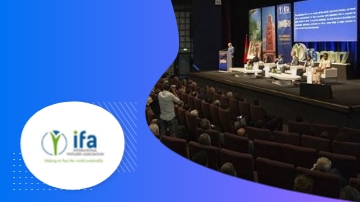 People on stage and audience in an auditorium with IFA logo on a blue background.