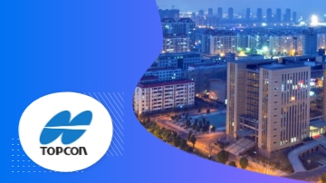 Topcon logo and a city skyline with buildings and illuminated streets at night.