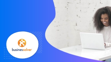 Woman sitting at a desk with a laptop and a Businessolver logo in the corner.