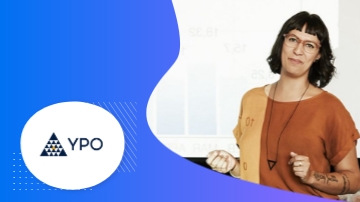 A woman stands in front of a white screen with YPO written on it.