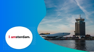 A photo of Amsterdam, featuring buildings, a body of water, and the text "I Amsterdam."