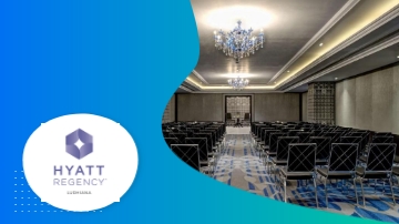 A conference room at Hyatt Regency with chairs, a chandelier, and a blue and green carpet.