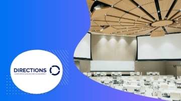 A room with a large screen, tables, and chairs with a logo "Directions" on the left side.