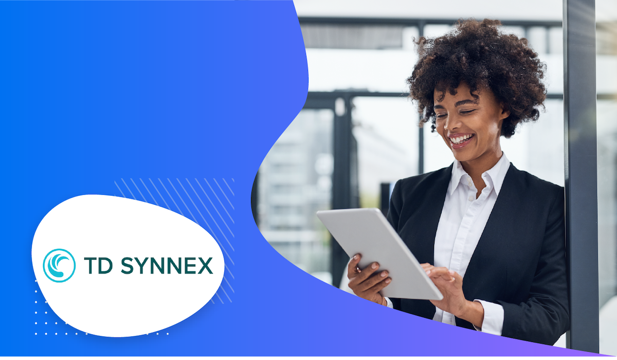 Woman using a tablet while standing in a glass-paneled room with the TD SYNNEX logo on the side.