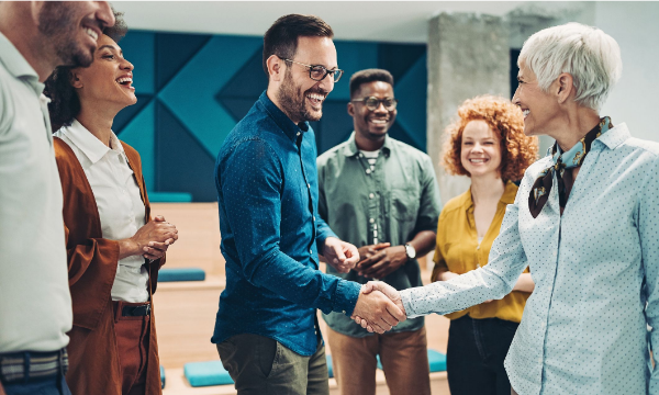 Diverse group of people in a meeting shaking hands in a modern office setting.