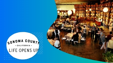 People at a large indoor event space with "Sonoma County, California: Life Opens Up" text.