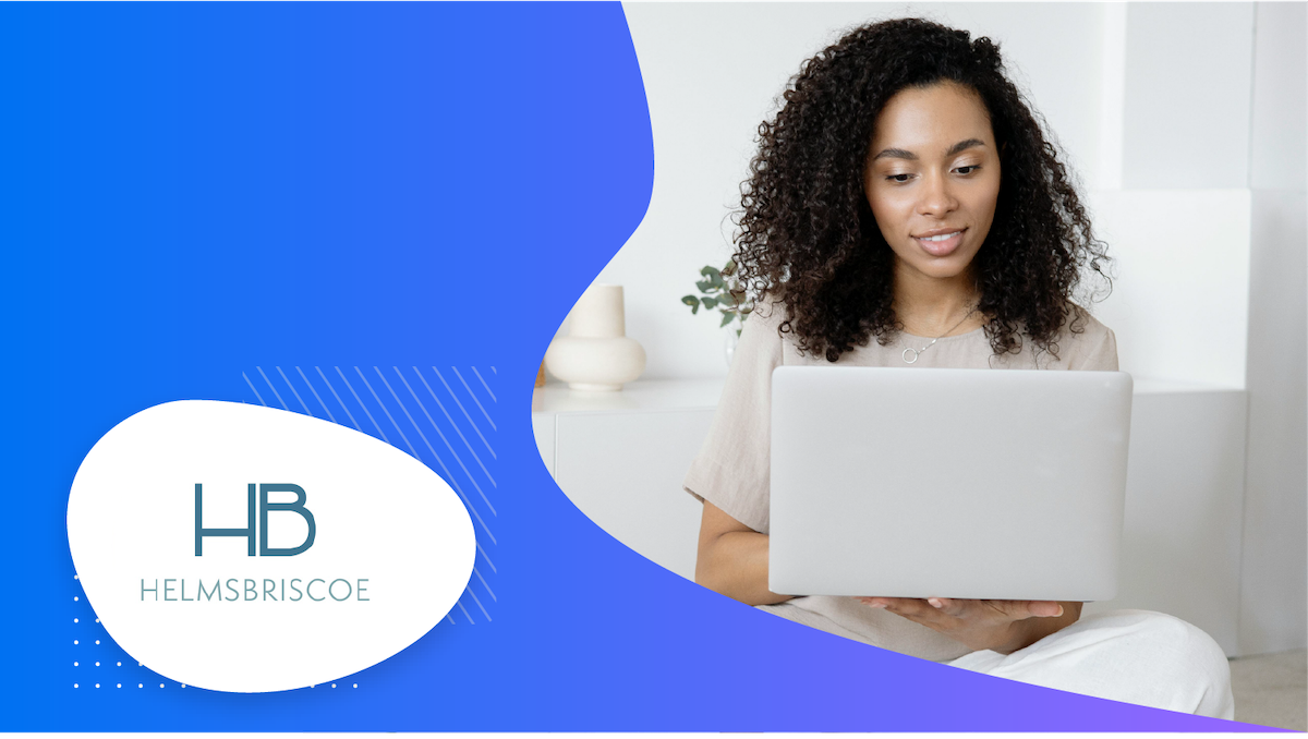 A woman holding a laptop while sitting on a couch in her living room.