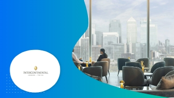 Two people sitting in chairs inside a lounge with a city view.