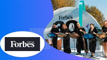 Forbes magazine banner and a band playing music in front of a round arch structure.