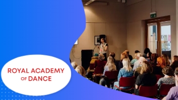 The Royal Academy of Dance is having a lecture with many people sitting on chairs and listening.