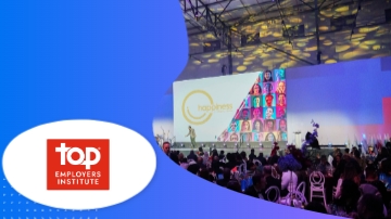 People gathered in a hall with the Top Employers Institute logo and a large screen in the background.