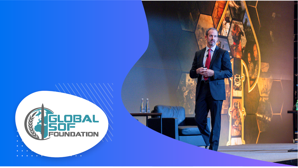 Man presenting at a confrence on a stage in a blue suit 