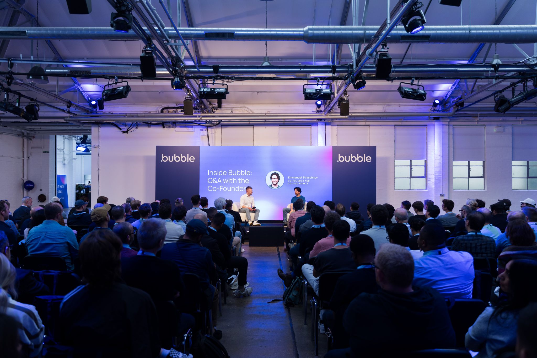  two speakers on stage and having panel discussion with audience
