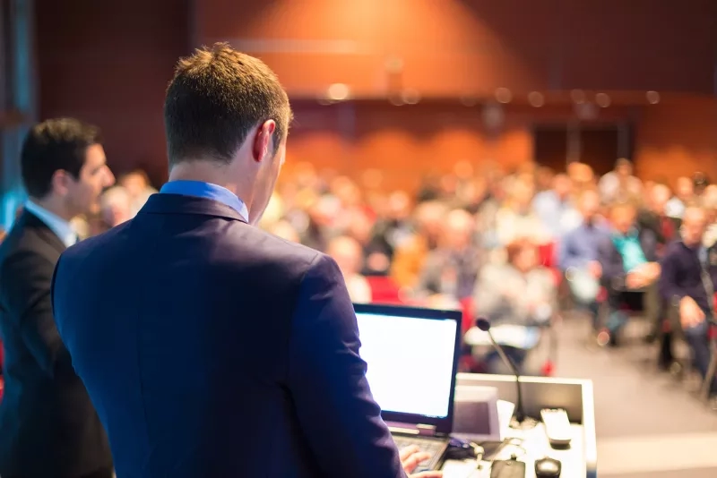 Man giving a presentation to a group of business people at a conference or seminar