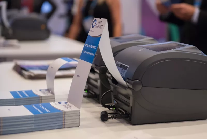 ON Arrival badge printer with name tags and event materials on the table.