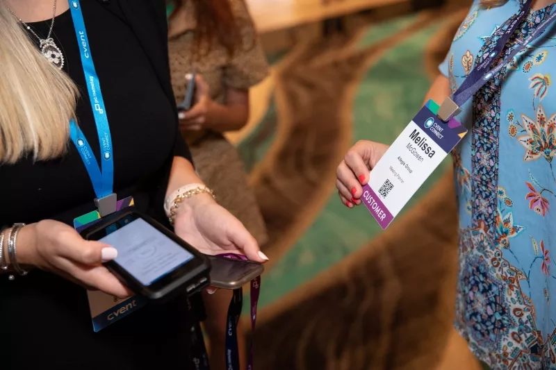 Woman scanning another woman's badge at an event with a Cvent Connect badge.