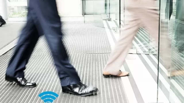 Two people walking through a glass door with a Wi-Fi symbol in the foreground.