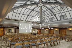 Chairs arranged in rows in Alcron Hotel Prague's conference room with glass ceiling and hotel logo.