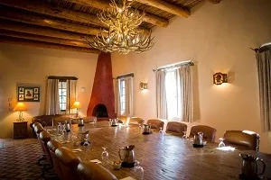 Conference room with a large table, leather chairs, chandelier, fireplace, and windows at Rancho de la Osa.