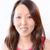 A woman with brown hair wearing a red top and necklace poses for a photo.