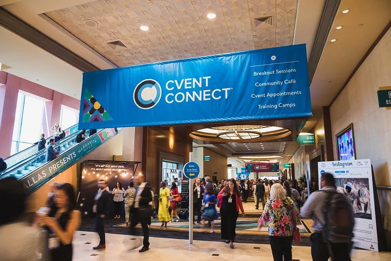 A busy event in a convention center with a Cvent Connect banner hanging from the ceiling.