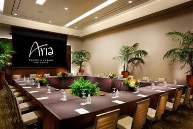 A meeting room at Aria Resort and Casino with a long table, chairs, and a projector screen.