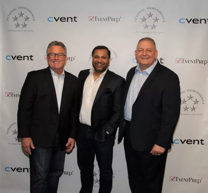 Three smiling men standing in front of a white wall with logos of "Federal Conference" and "Cvent."