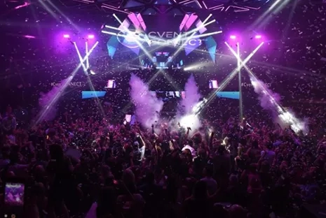 Large crowd of people attending Cvent Connect conference in a dark room with colorful confetti and lights.