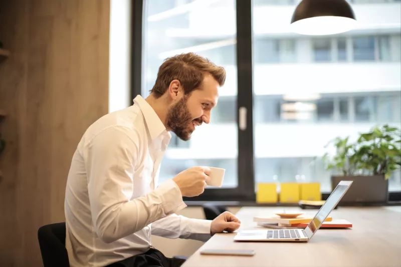 A man is running a virtual meeting with a laptop in his office.