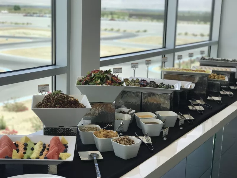 Buffet of salads, nuts, fruits, and other appetizers with a view of the racetrack
