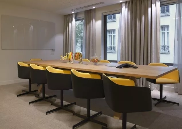 Meeting room with long table, chairs, windows, and building view in Hotel Le Mareuil, Paris.
