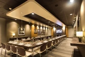Meeting room with long table, chairs, and TV in the background.