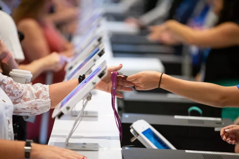A woman is scanning her badge at a table, while another woman is looking on.