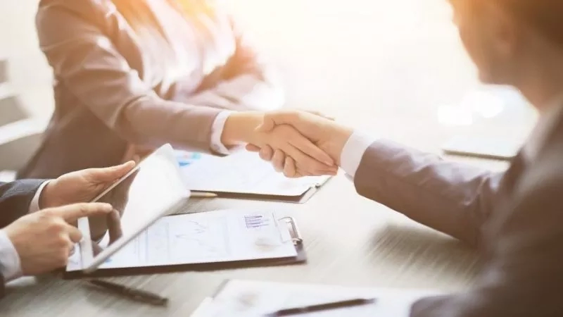 Business people shaking hands in a meeting, symbolizing partnership or agreement.