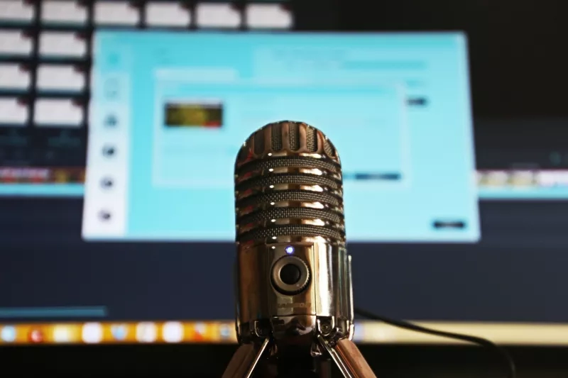 Microphone in front of a computer screen with a blue background and a website on the screen.