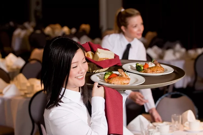 A server carrying food on a tray to serve to guests at a function at the hotel.