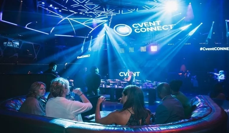 Group of people sitting at a table in a bar with Cvent Connect written on the ceiling.