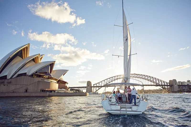 A boat is sailing in the sea, with the Sydney Opera House in the background.