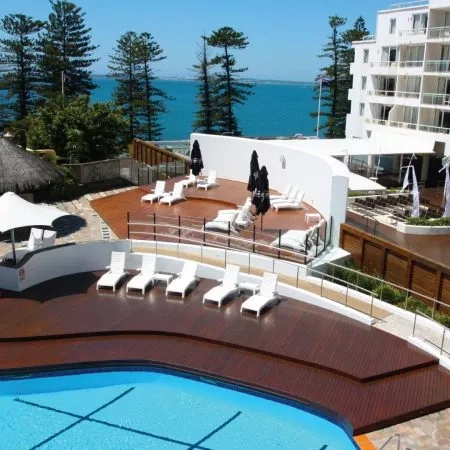 Novotel hotel with a view of the ocean, featuring a swimming pool and sun loungers.