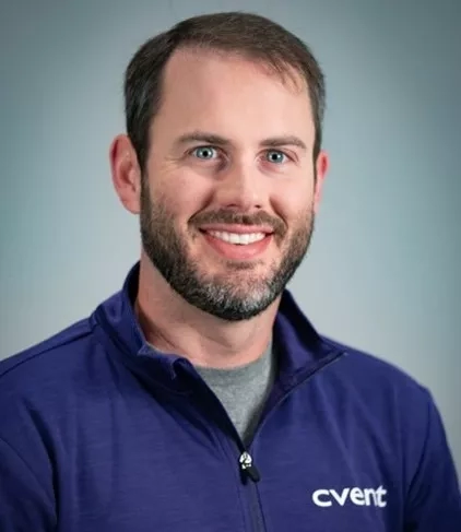 Portrait of a smiling bearded man in a blue shirt with the word "cvent" printed on it.