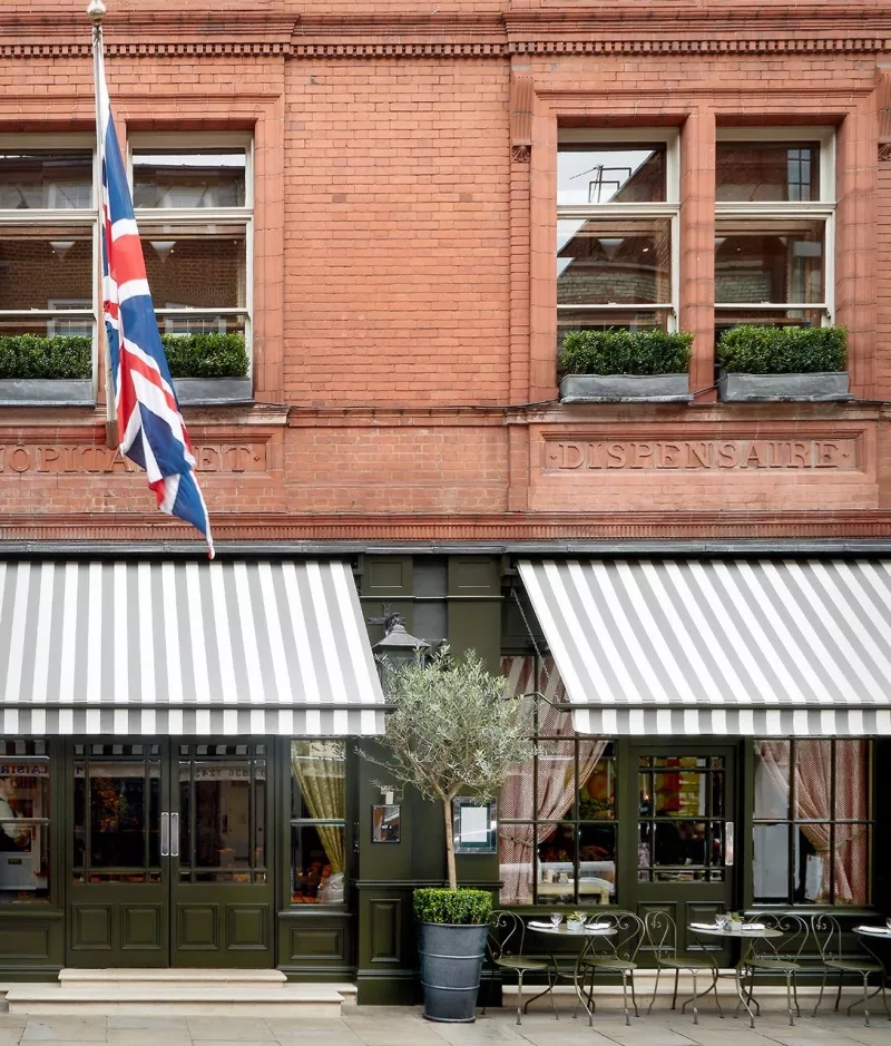 Exterior view of the restaurant with a flag, brick architecture, landscaping, and outdoor seating arrangement.
