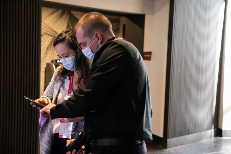 A man and woman wearing masks, each looking at a phone in a lobby at MGM Grand.