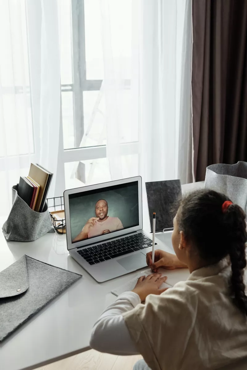 Woman working from home while a virtual event plays on her laptop screen.