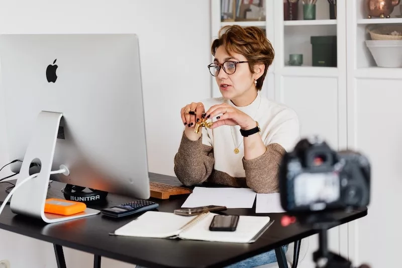 Woman sitting at a desk speaking into a camera while holding a set of keys.