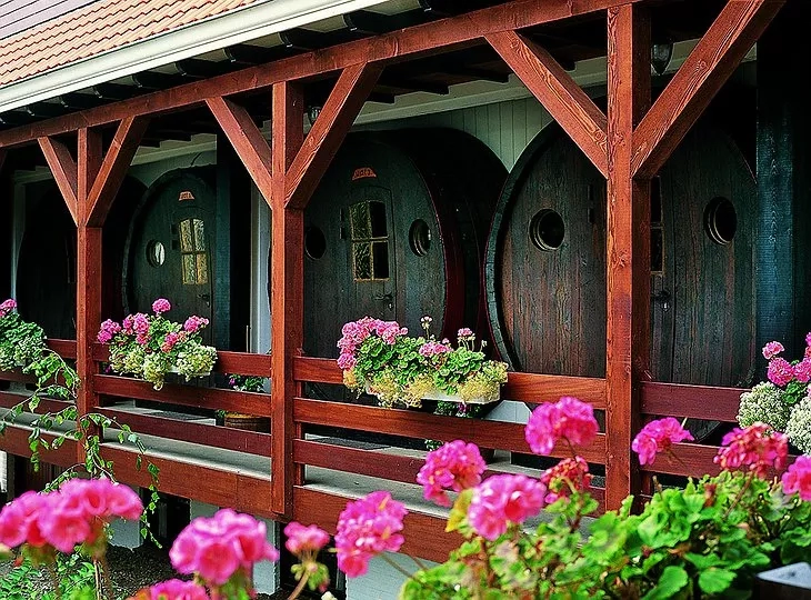 Wooden barrel cellar with red flowers in front of the wooden fence at Hotel De Vrouwe van Stavoren.