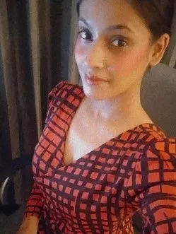 Prachi is an attractive woman wearing a red and black dress in a room with curtains.